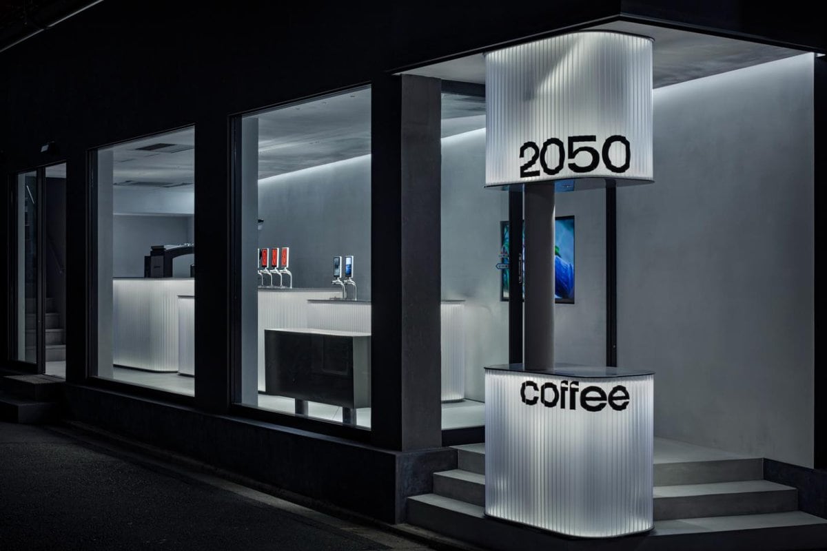 Modern coffee shop exterior with illuminated signage and sleek design elements at night.