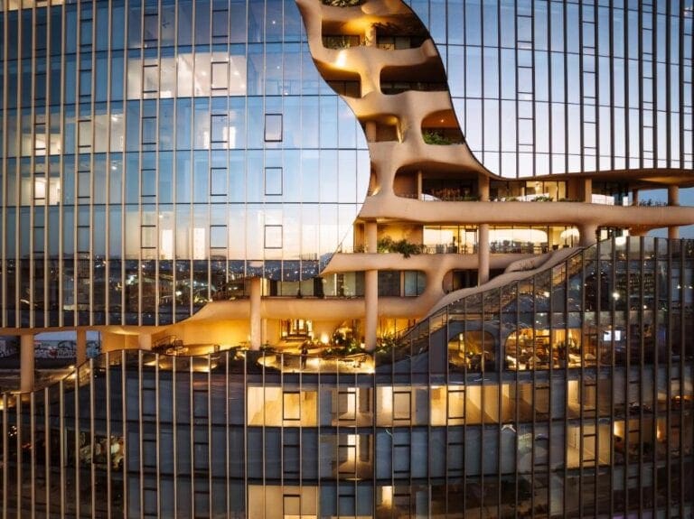One River North by MAD a new vision of urban living in Denver Modern architectural building with innovative design and glass facade at dusk.