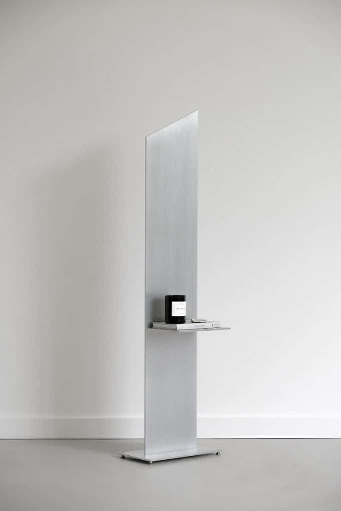Minimalist retail display with sleek metallic stand and product on shelf, modern interior design.