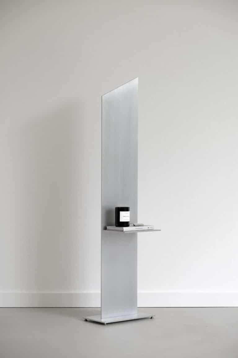 Minimalist retail display with sleek metallic stand and product on shelf, modern interior design.