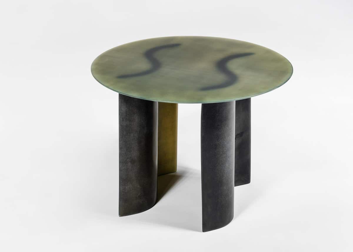 Contemporary sculptural side table with textured black and gold finish, round top, minimalist design.