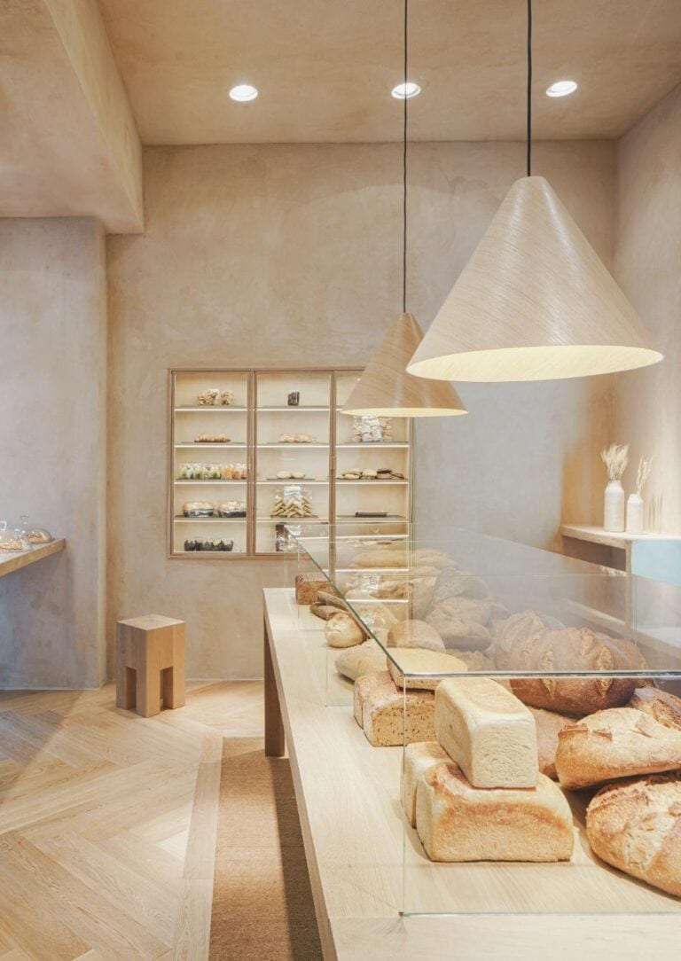 Zooco Estudio design El Horno de Babette as inviting bakery spaces Rustic bakery display with bread and stone details, warm modern interior design.