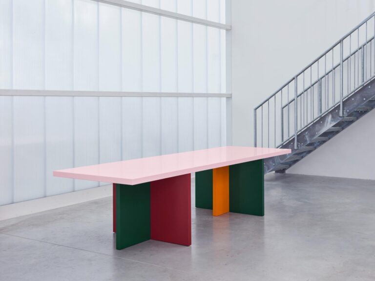 Abbondio, an award-winning customizable table by Bannach Colorful modern dining table with geometric legs in an industrial-style room.