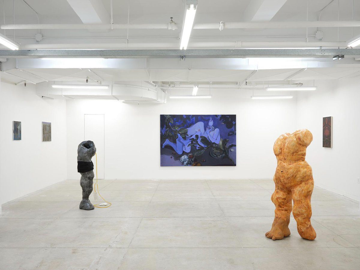 Abstract modern art exhibition with sculptures and paintings in a minimalist gallery space.