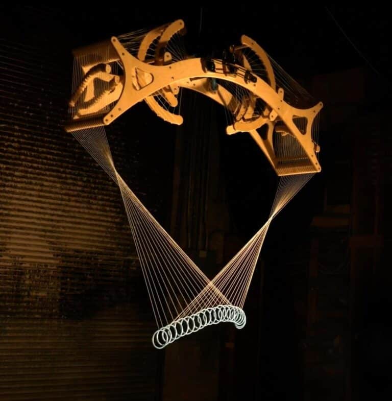 Interview with Reuben Margolin on his mesmerizing kinetic sculptures Suspended wooden mobile art installation with string lights in a dark space.
