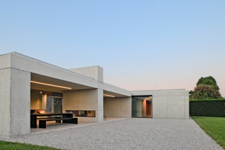 160_Villa by MIDE Architetti, where functional design meets natural elegance Modern minimalist concrete house with large glass windows and outdoor patio.