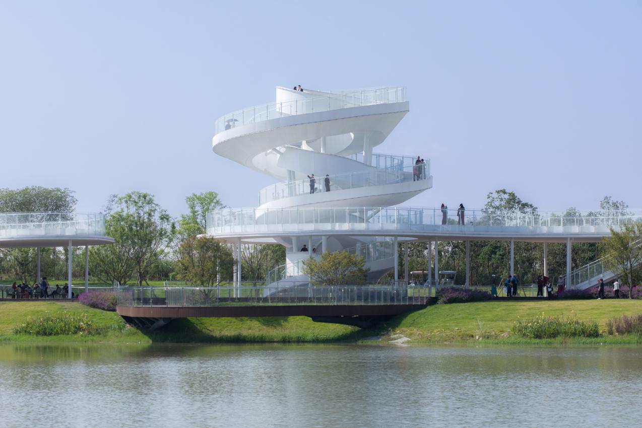 Futuristic white observation tower with spiral staircase structure in a park setting, reflecting modern architectural design.