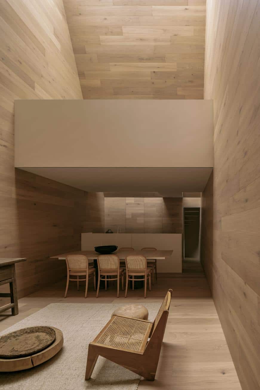 Contemporary minimalist dining room with wood-paneled walls and modern furniture design.