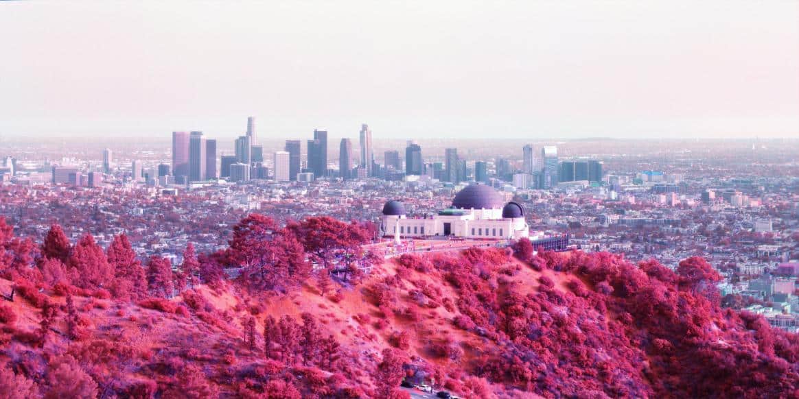 Vibrant pink Los Angeles skyline with Griffith Observatory and downtown skyscrapers, showcasing urban and natural landscape.