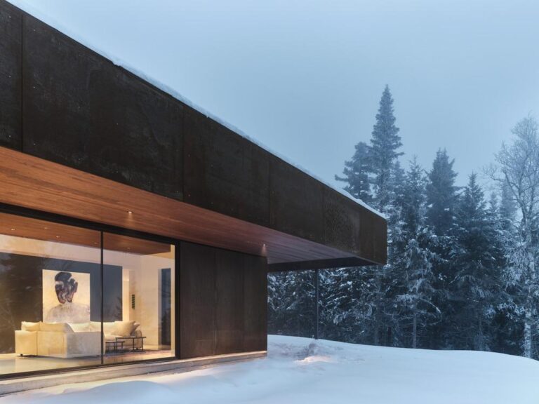 a house with a large window and a snowy hill