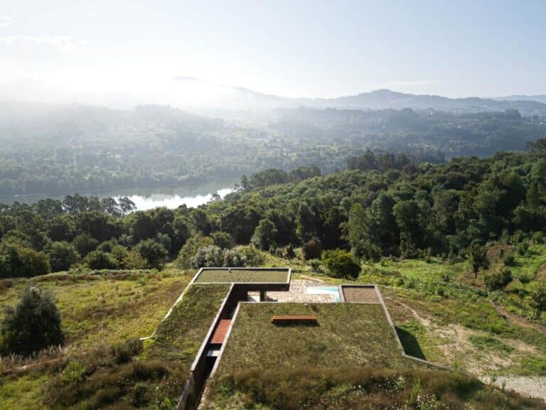 Casa da Levada by Tsou Arquitectos, a sustainable home in Penafiel Serene landscape with modern house overlooking lush green hills and a distant river view at sunrise.