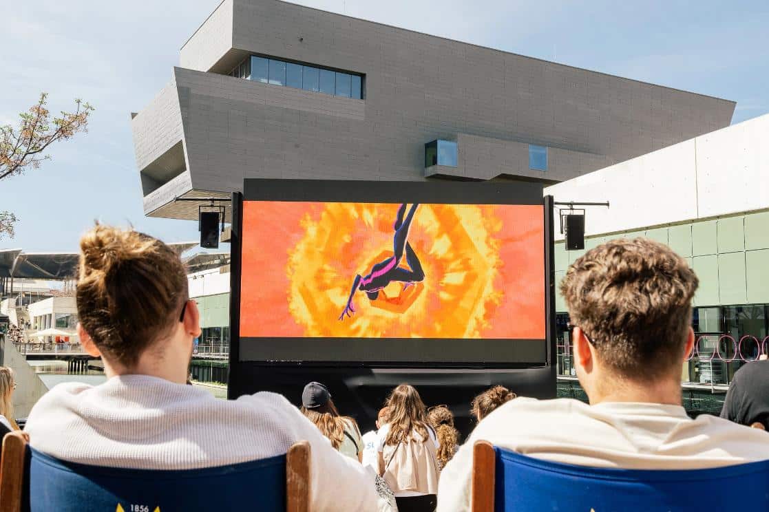 Aerial view of outdoor movie screening event with large LED screen showcasing a digital animation.