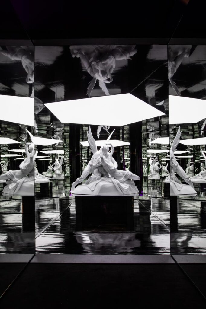 Mirrored art installation reflecting human silhouettes in an infinite digital loop