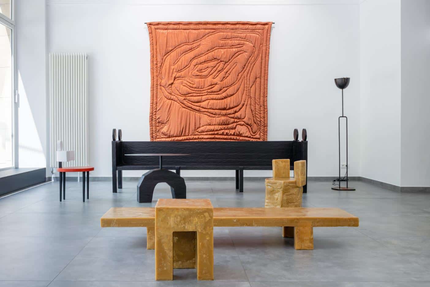 Colorful modern art sculptures and a textile wall hanging exhibit contemporary interior design.