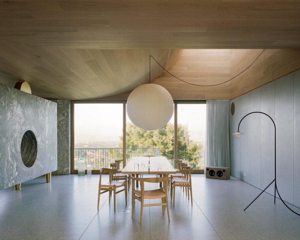 Minimalist kitchen and dining area flooded with natural light from clerestory windows in WOJR’s House of Horns