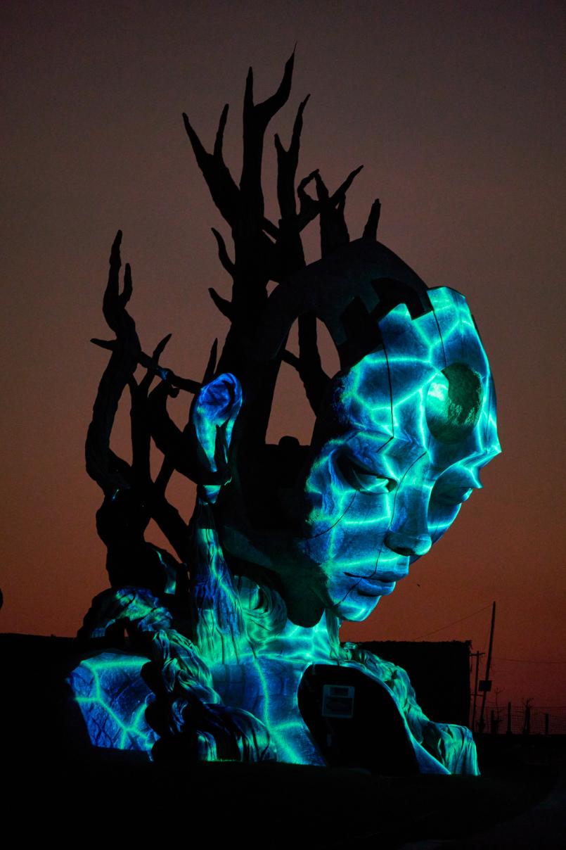 Vivid illuminated sculpture of a human face with digital art effects at night.