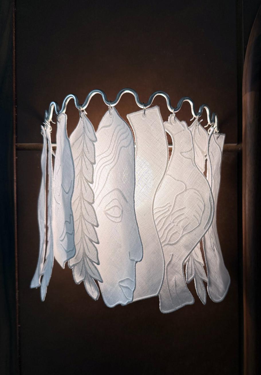 Delicate fabric swatches with embossed artistic designs hanging on a wavy hanger.