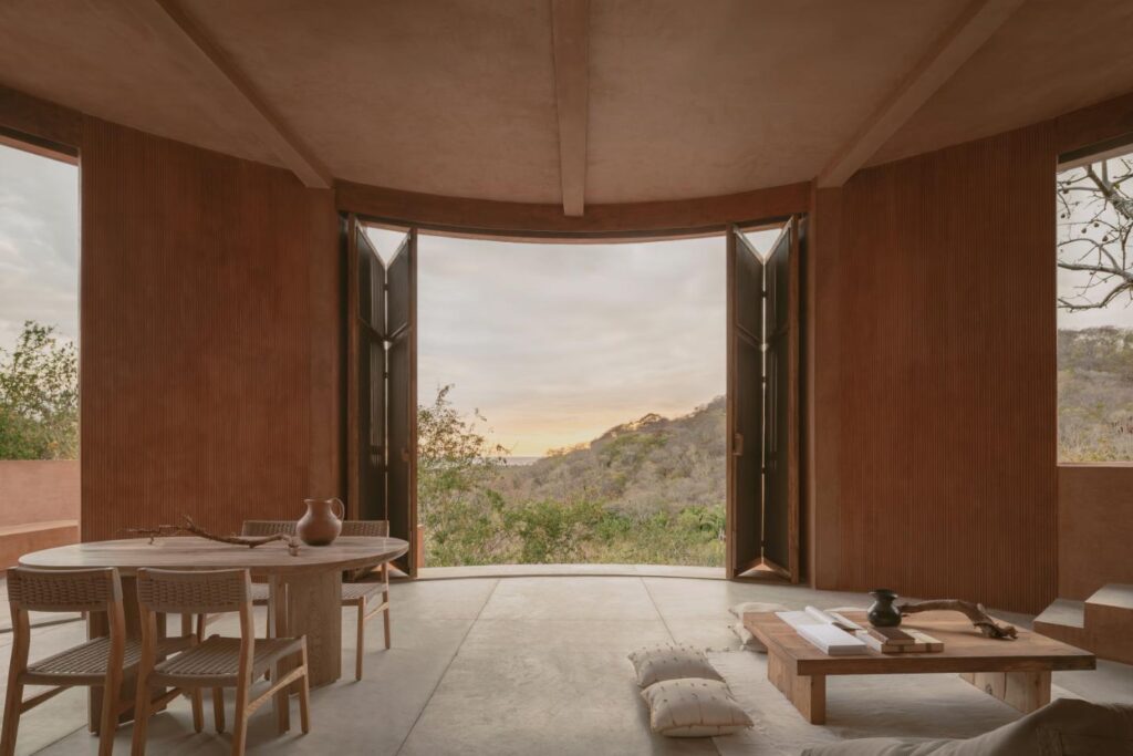 Interior double-height living area with panoramic views of the Pacific Ocean and lush hills