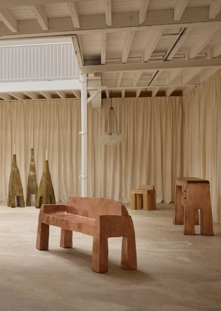 Asymmetrical metal bench placed centrally on concrete flooring within the minimalist Solo Show installation space