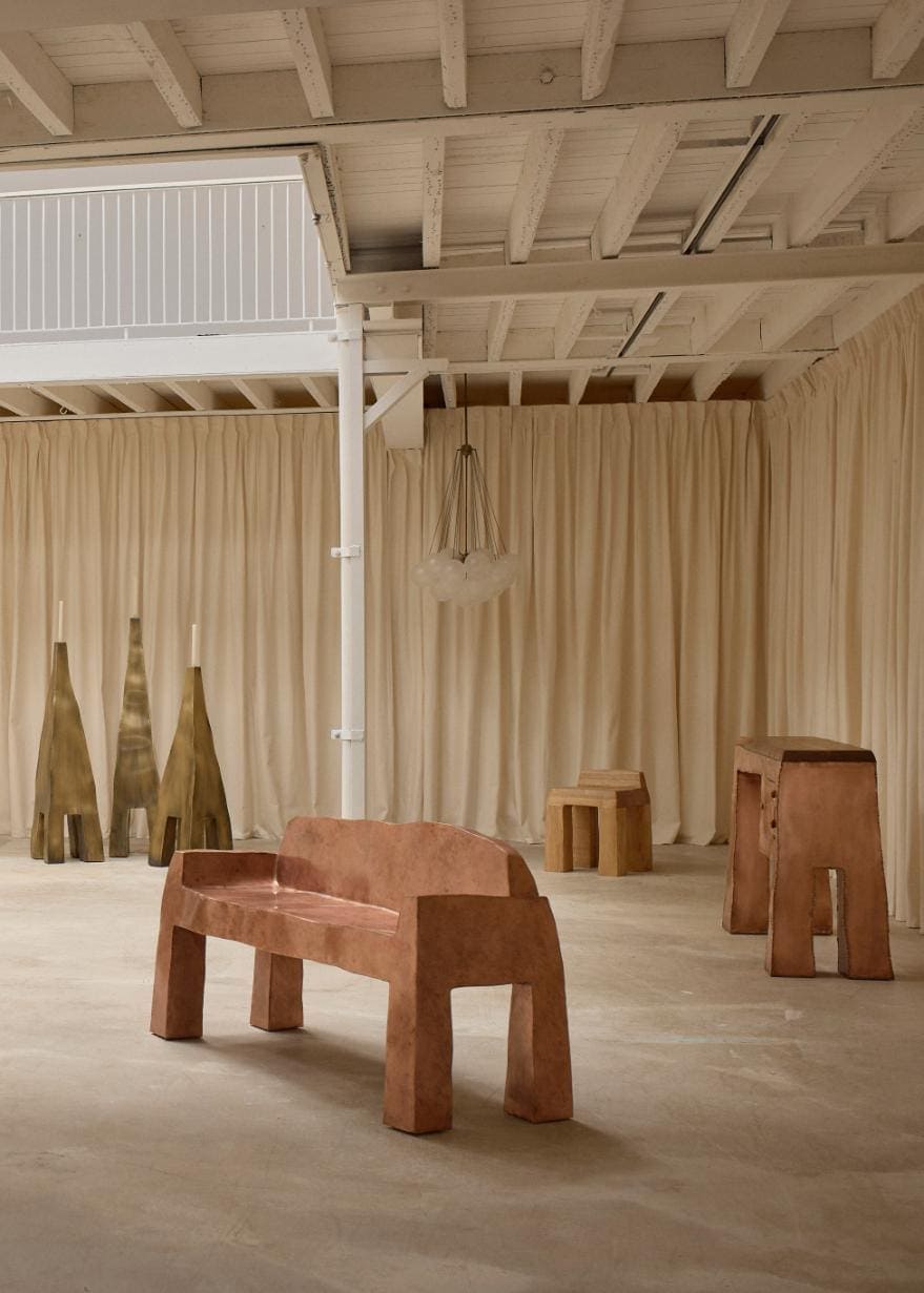 Asymmetrical metal bench placed centrally on concrete flooring within the minimalist Solo Show installation space