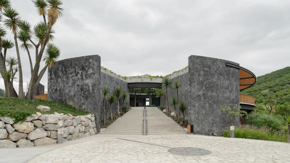 Curved stone walls rising from the hillside of La Pedrera Clubhouse