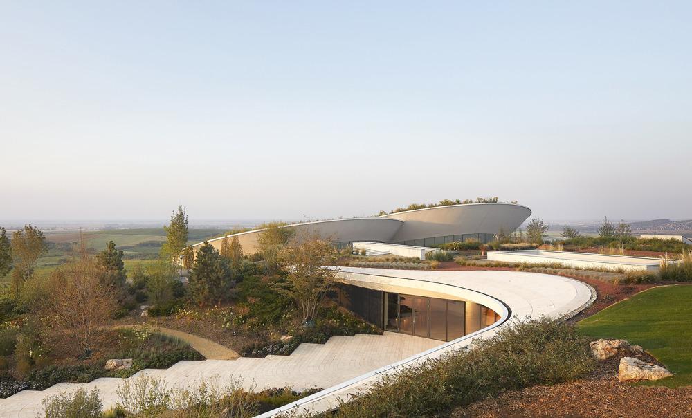 Glass and steel structure of Sauska Tokaj winery framed by panoramic vineyard views