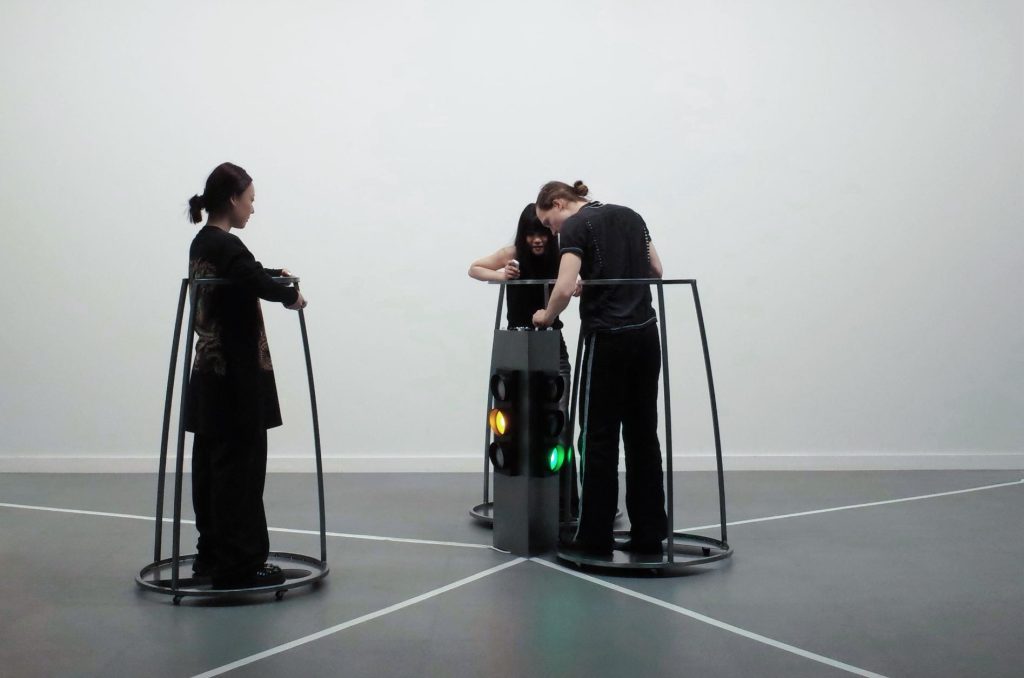 Participant pausing within the triangular space as shifting lights indicate control and withdrawal in the game.