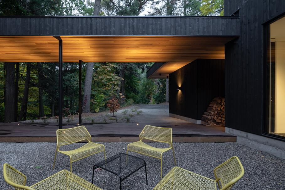 Outdoor gathering space with covered patio overlooking forested ravine