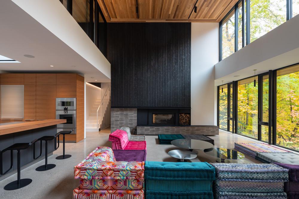Living room with expansive windows and repositioned fireplace creating a warm focal point