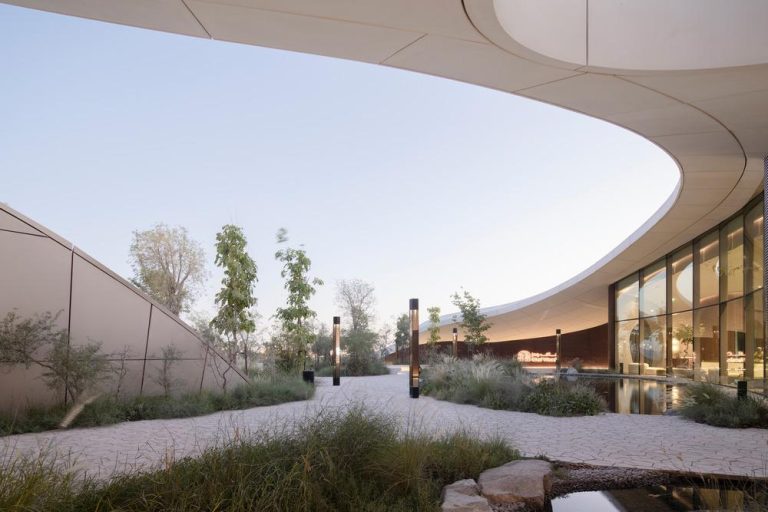 aoe designs sustainable Ghaf Woods Experience Centre in Dubai Floor to ceiling glass wall opening to landscaped pond and forest canopy views