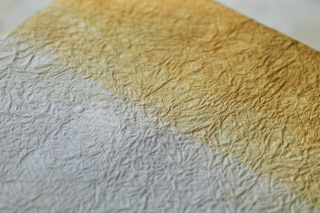 Handmade washi paper sheets suspended with soft gradients of purple and gold.