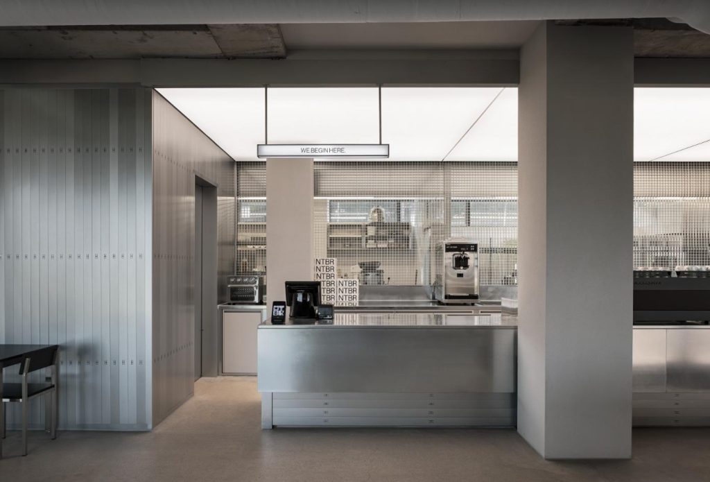 Grated ceiling structure inside NTBR café extending spatial axis of display