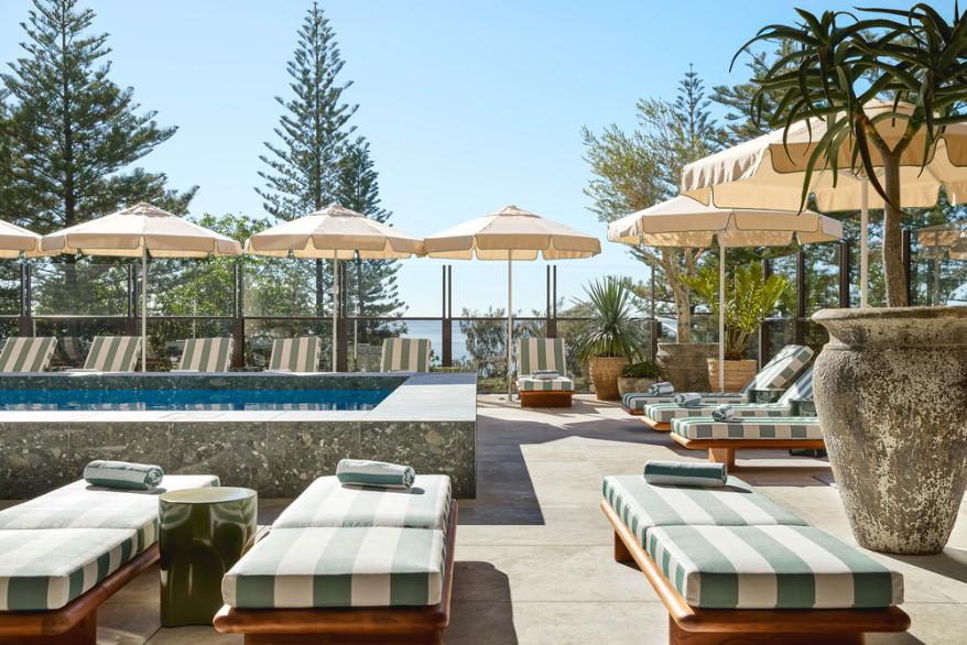 Pool Club terrace with sunbeds, umbrellas, and ocean views from the third floor