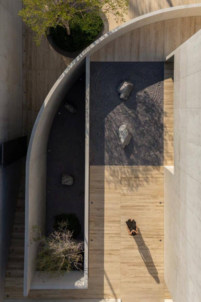 Curved entrance wall leading visitors toward a shaded courtyard