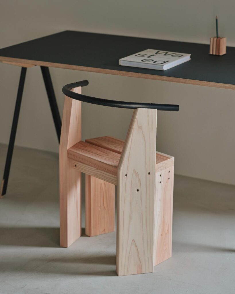 Hiroi Chair placed under a wooden table showing its compact form