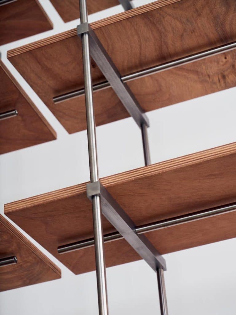 Close-up of the okoumé plywood grain contrasting with polished steel rods