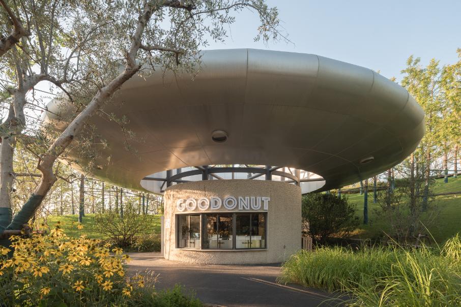 Silver disc dessert kiosk reflecting daylight beside vegetation