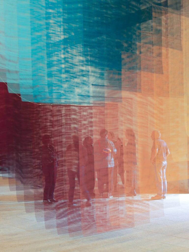 Visitors walking beneath luminous colored planes shifting with perspective