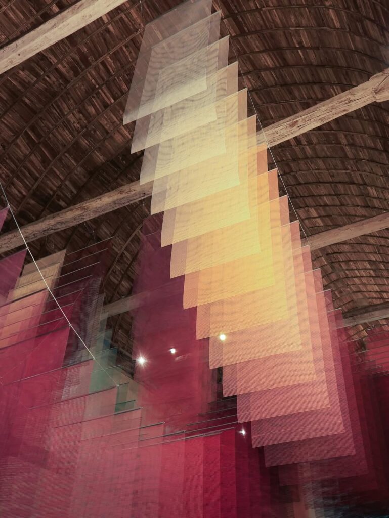 Suspended translucent panels creating layered color effects inside the chapel