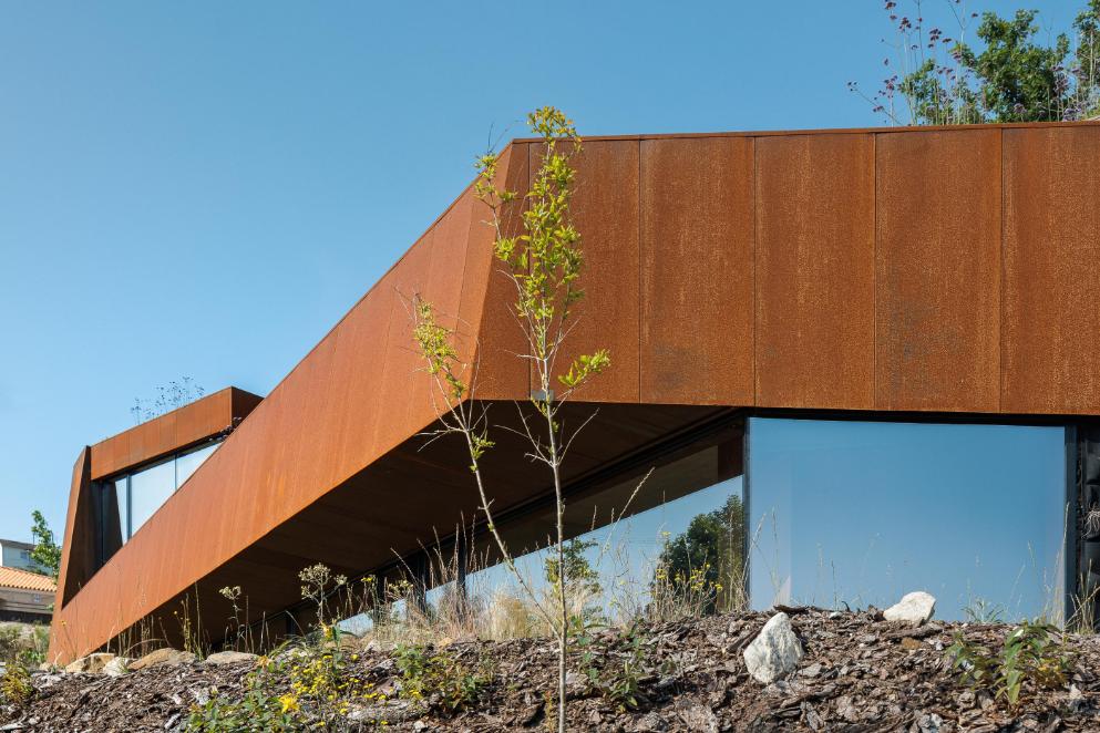 Casa Corten by HPA Arquitetura on a sloped industrial site -