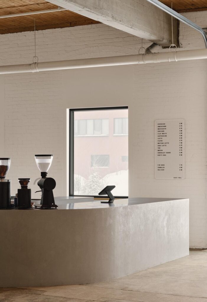 Café area with curved microcement counter opening to Parc des Gorilles