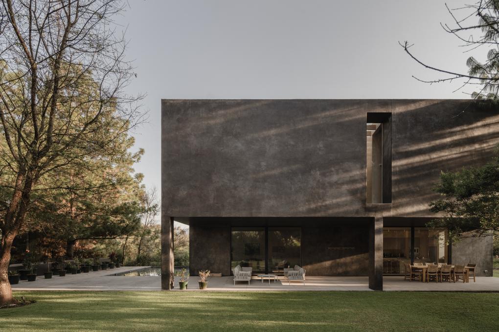 Exterior of Casa Ocote reflected across a calm water surface