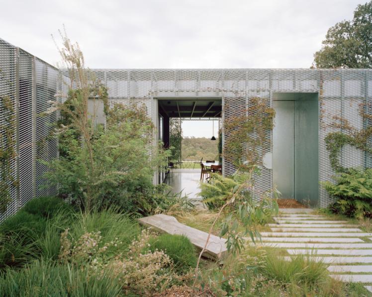 Hedge and Arbour House mediates suburban street and native bushland Exterior hedge boundary with arched entry framing the suburban footpath
