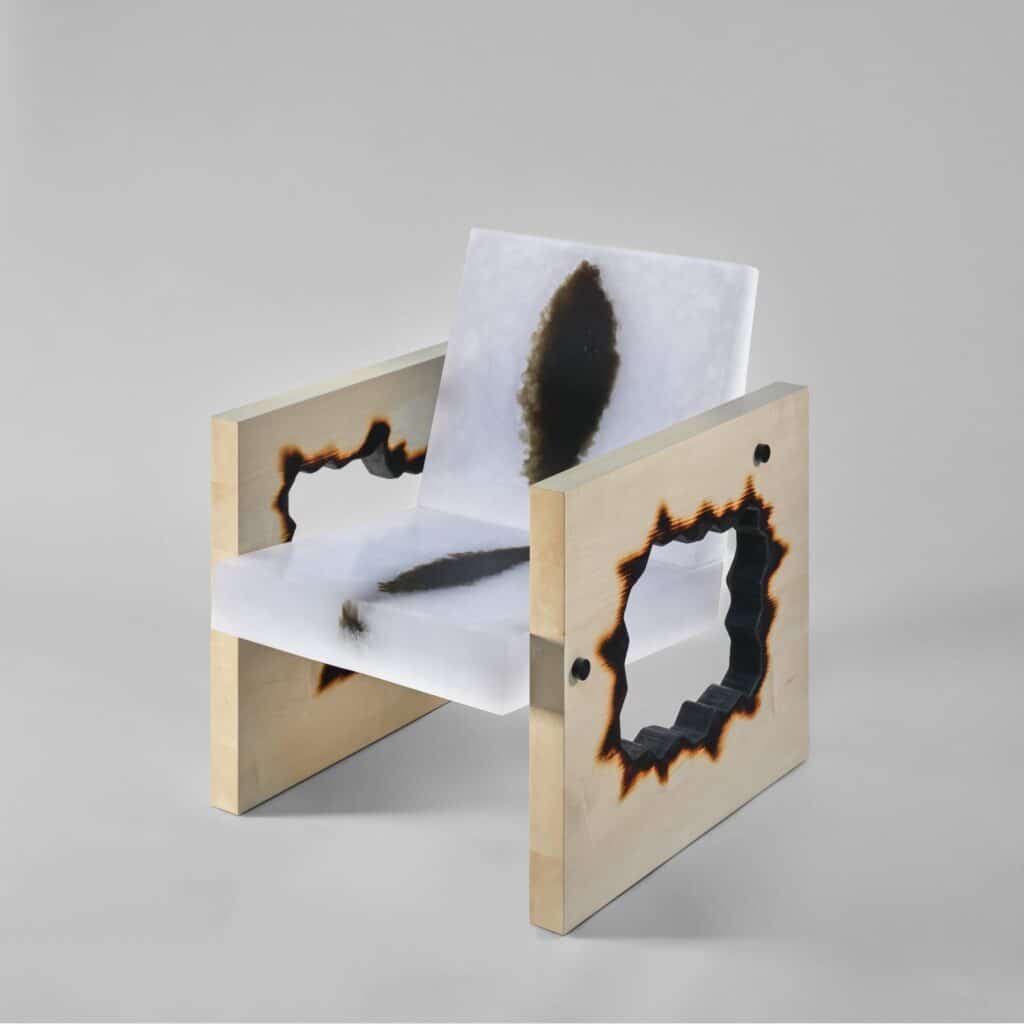 Cast recycled glass armchair supported by charred maple frame at Design Miami