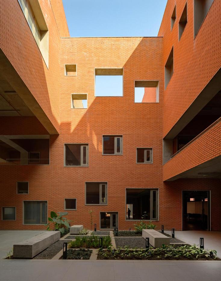 Courtyard elevation with varied window sizes puncturing brick walls around planted beds