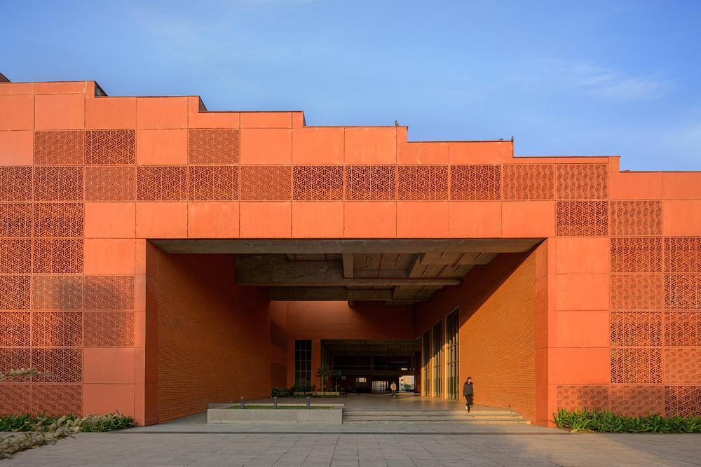 Covered passage with brick walls, glazed edges and concrete slabs leading into the building