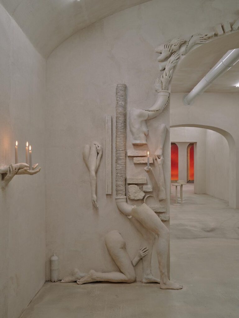 Plaster relief figure integrated into the wall beside an archway in the installation