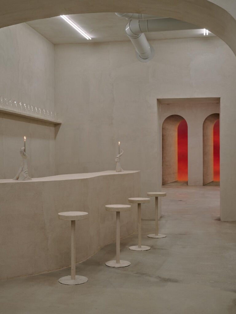 Bar counter with round stools and sculptural candle-holding hands