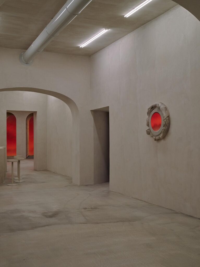 Room view with circular wall relief framing a red-lit oval opening in Bar Far