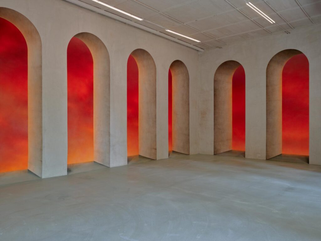 Arched wall niches lit in red and orange inside Villa Lontana Trastevere
